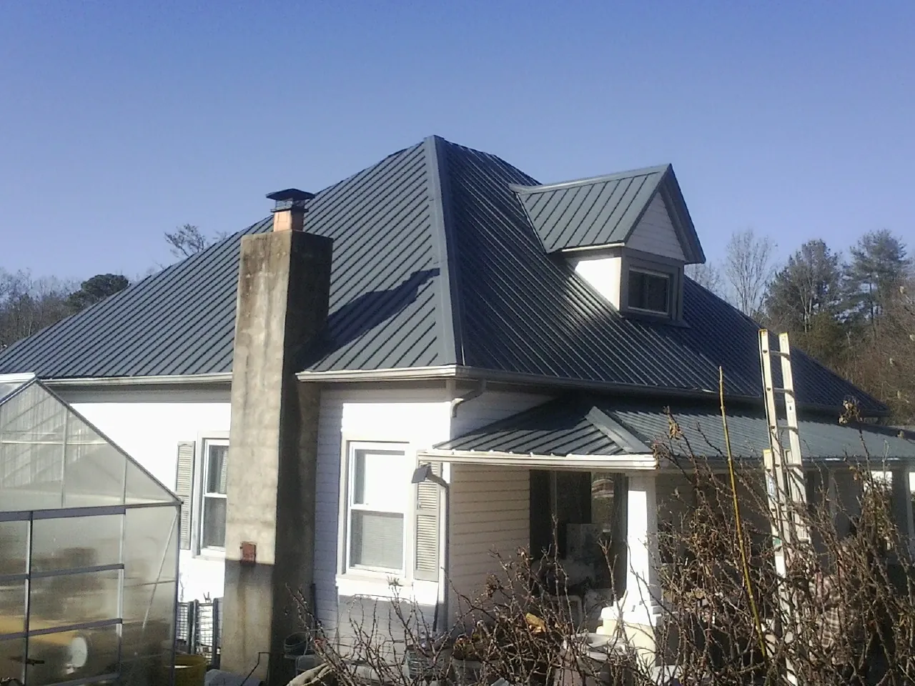 Dark blue standing seam metal roof on a white farmhouse with dormer — Slate & Tile Roof Repair by Roofing Brothers in Scottsburg