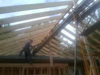Rafters going up over a new addition with a worker on the wall in Scottsburg