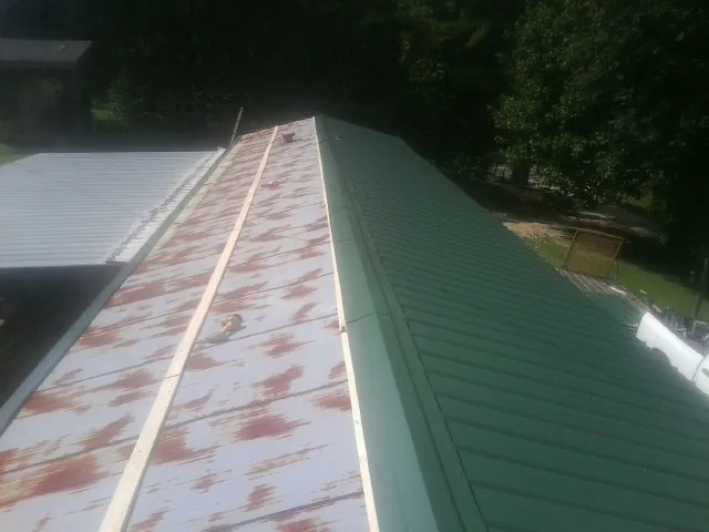 Old rusted panels beside newly installed green metal roofing — Wind Damage Roof Repair by Roofing Brothers in Scottsburg