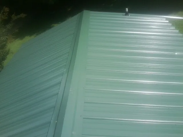 New green metal panels meeting at the ridge of a roof — Flat Roof Repair work by our crew in Scottsburg