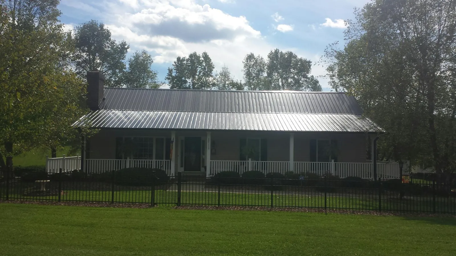 Gray metal roof on a brick ranch with a full width front porch — Gutter Guard Installation work by our crew in Scottsburg