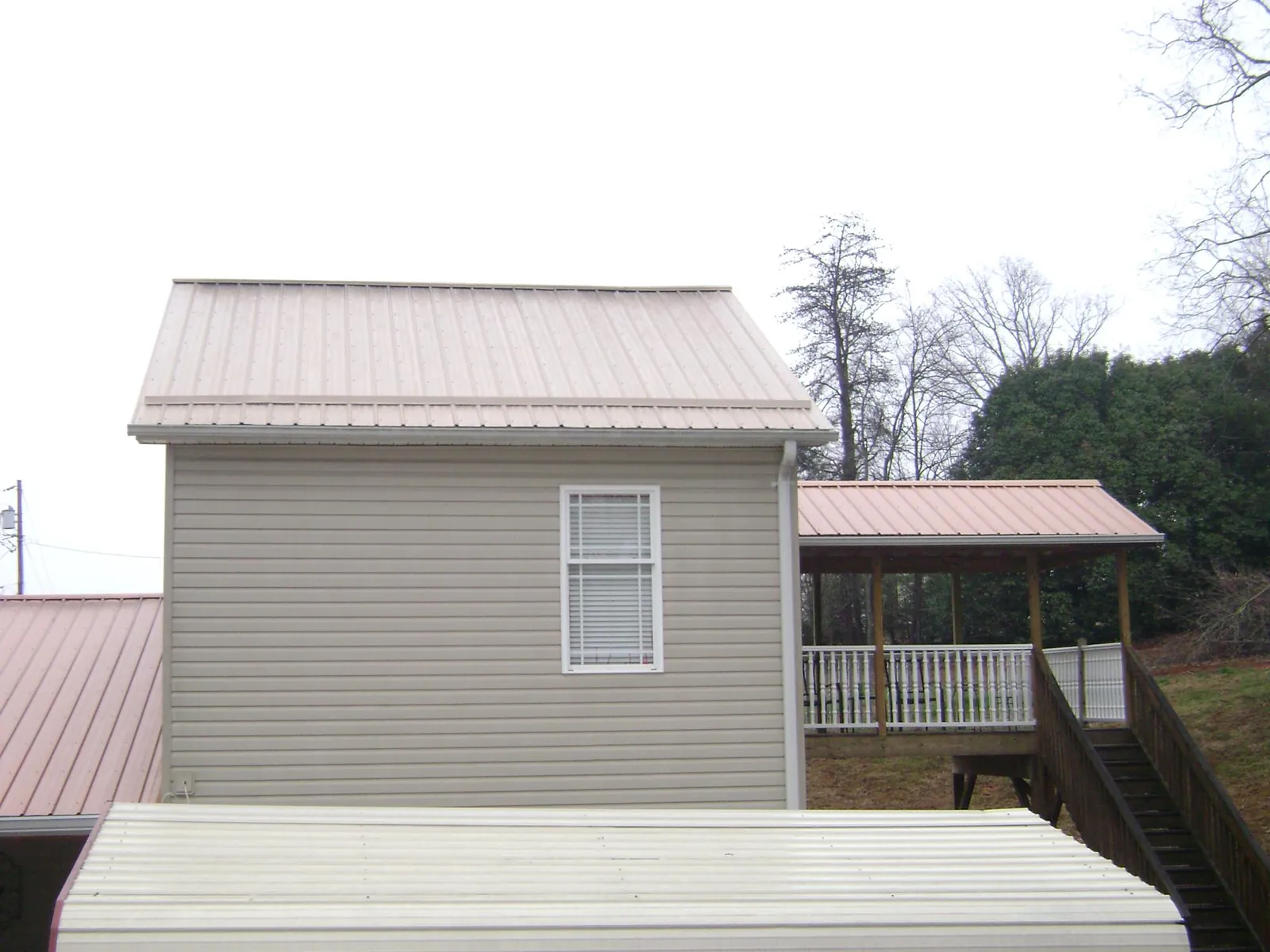 Tan metal roofs on a two story addition and attached porch, from a Roof Replacement job in Scottsburg